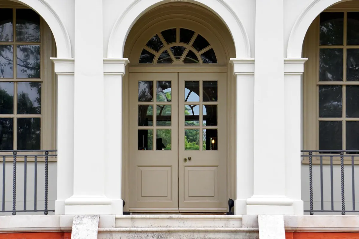 Glazed double French doors with an arched fanlight transom set in a white facade